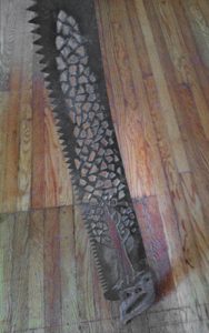 Photo of old saw with plasma-cut tree design cut into it.